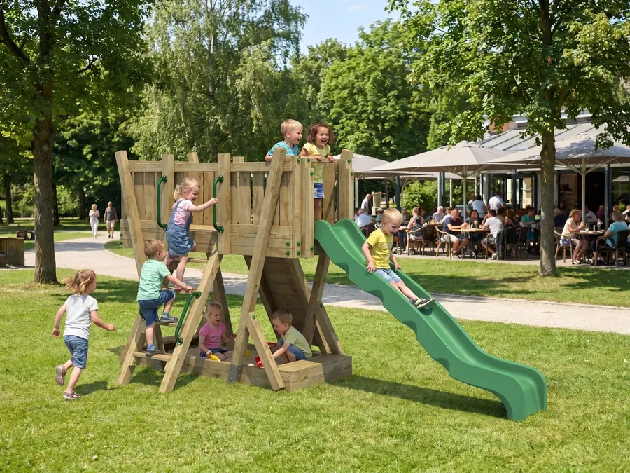 Kinder klettern und rutschen an einem öffentlich aufgestellten Spielturm neben einem Gastronomiebereich