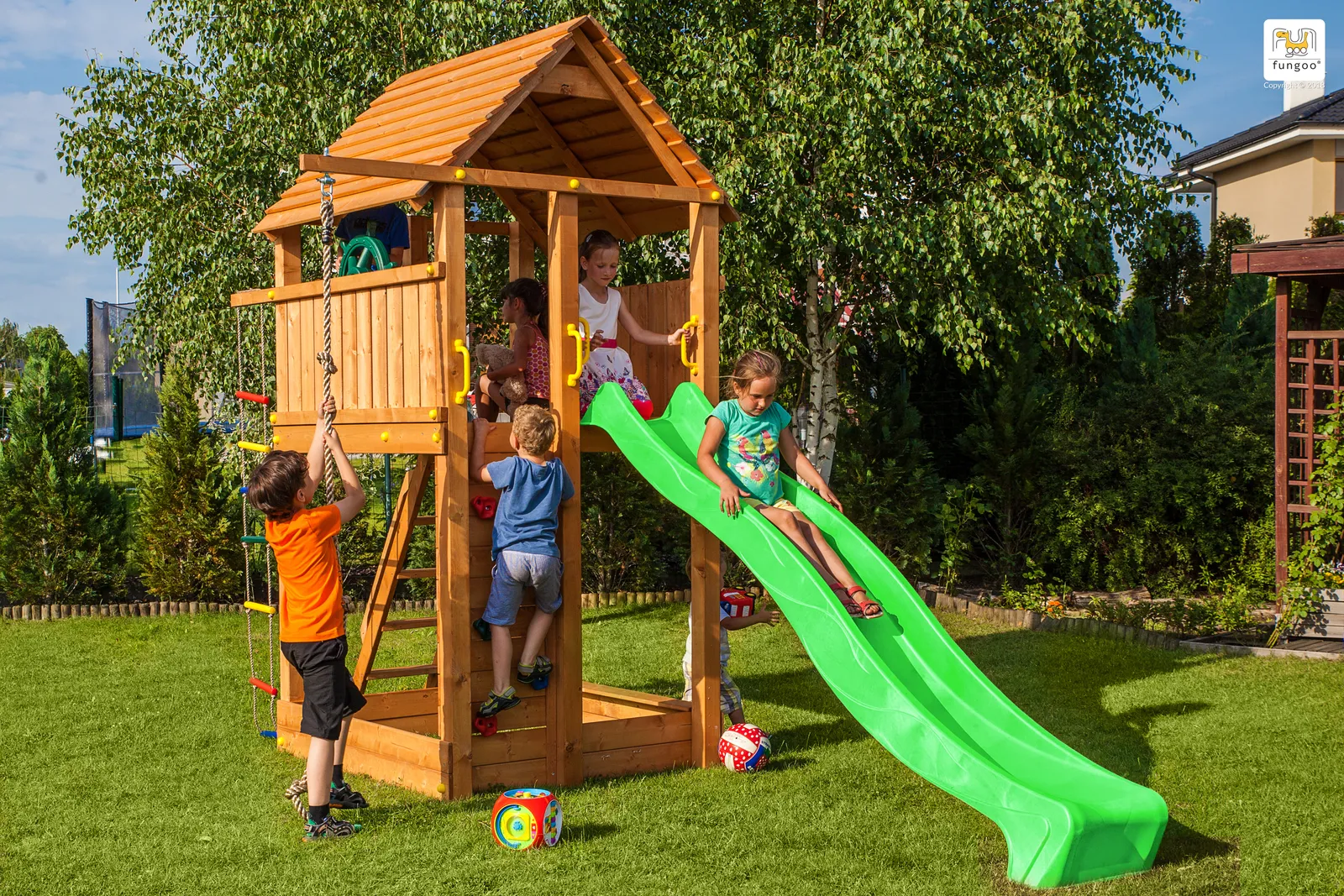 Mehrere Kinder klettern und rutschen gemeinsam an einem Fungoo-Spielturm